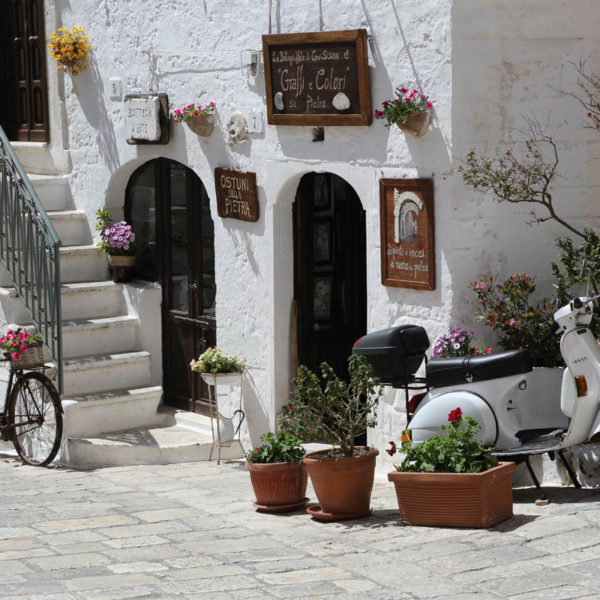 A bicycle, scooter and flower boxes by a shop in Ostuni in Italy. Ostuni is known as the 'white city' (Citta Bianca).